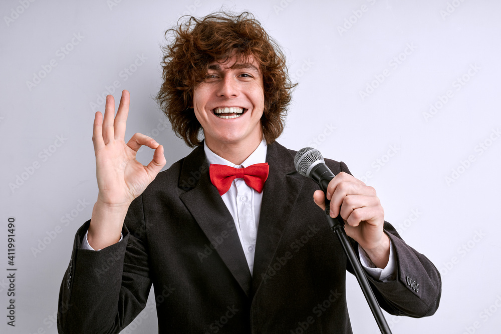 Naklejka premium artist in suit with microphone showing OK gesture and smiling, the presentation or speech is good, successful performance