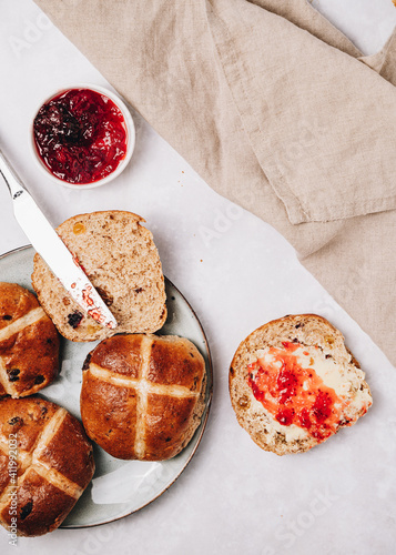Traditional English Easter Hot Cross Buns on a plate with jam and butter, top view