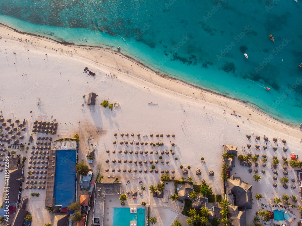 Aerial view of Thatched Roof Umbrellas Pattern on Wide Coastal line of White Sand of Kendwa Beach in Kendwa village, Zanzibar