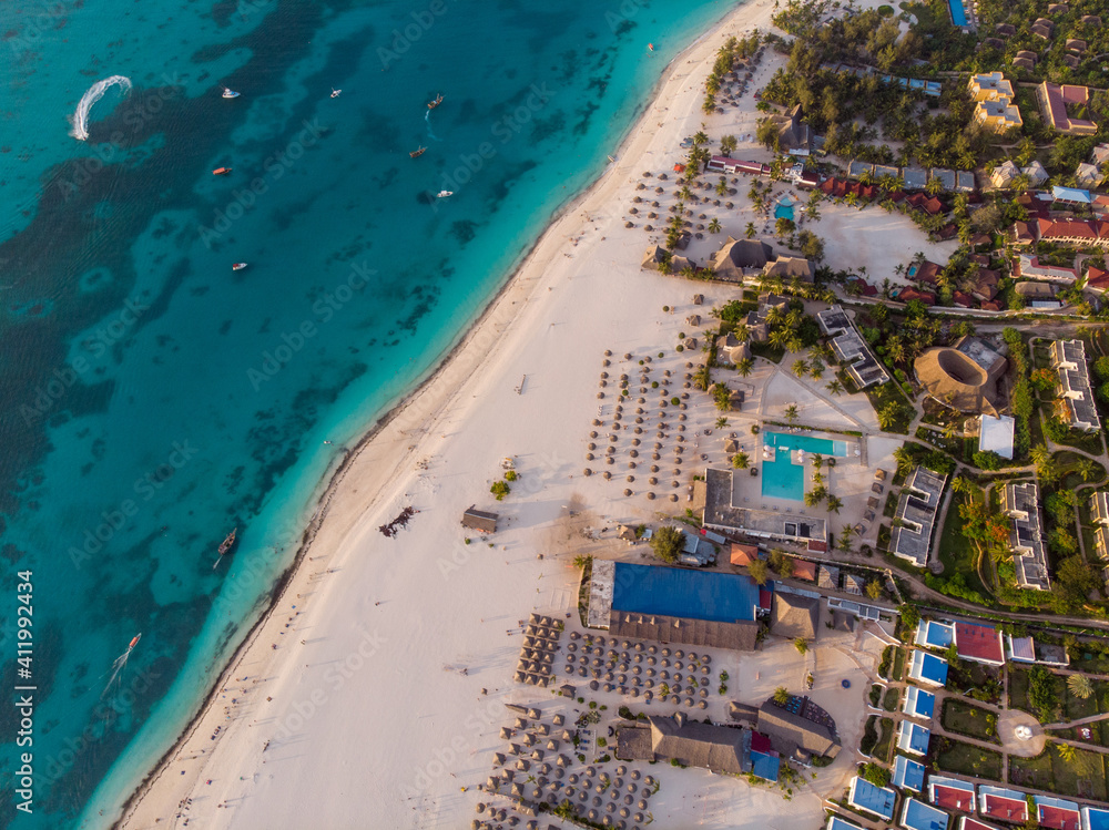 Aerial view of Thatched Roof Umbrellas Pattern on Wide Coastal line of White Sand of Kendwa Beach in Kendwa village, Zanzibar