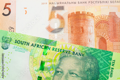 A macro image of a shiny, green 10 rand bill from South Africa paired up with a orange five ruble bank note from Belarus. Shot close up in macro.