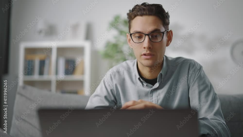 Serious man in eyeglasses talking and gesturing during video conversation on laptop. Worker having online meeting while staying at home. Serious man in eyeglasses talking and gesturing during video conversation on laptop. Worker having online meeting while staying at home.