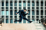 Businessman in a suit jumping in front of his offices