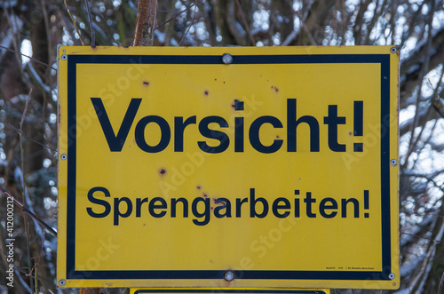Yellow sign reading caution blast on german