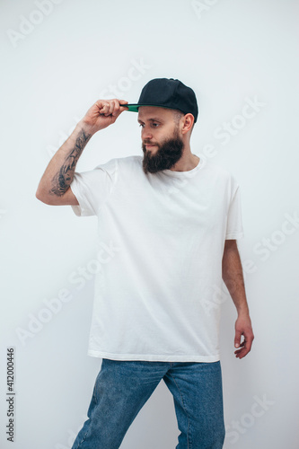 Young bearded hipster guy wearing white oversized blank t-shirt on a white background. Mock-up for print. T-shirt design and advertising concept.