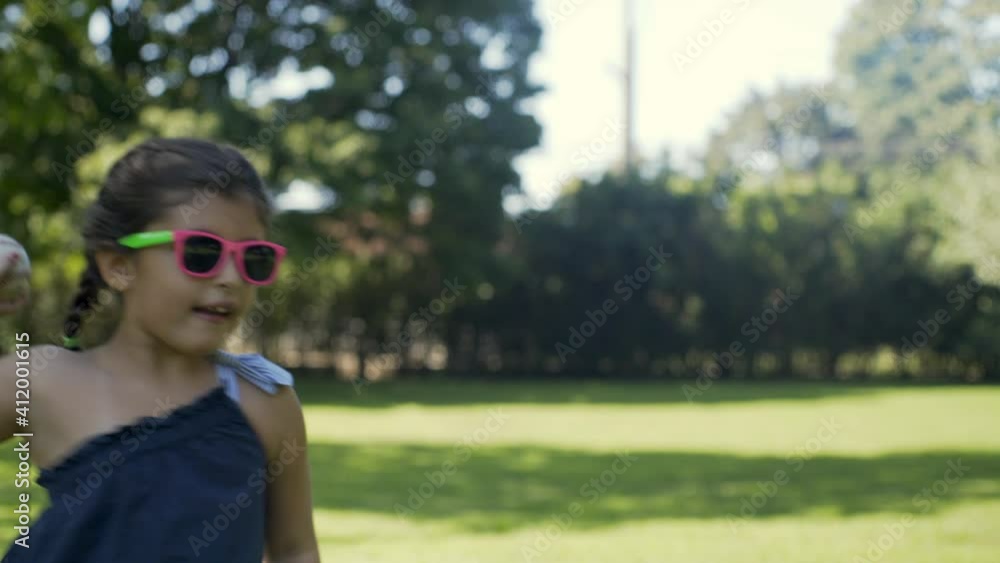 Young Girl Throws and Catches Baseball at the Park Young Girl Throws and Catches Baseball at the Park