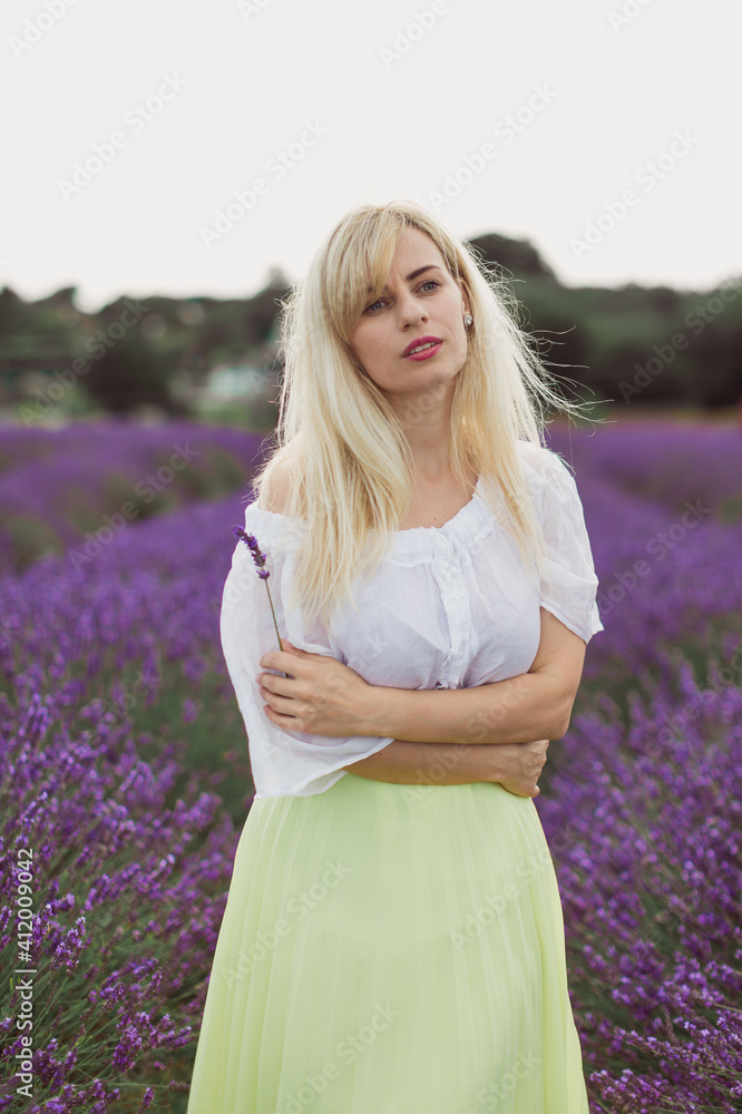 The young attractive woman is standing in the lavender field The young attractive woman is standing in the lavender field