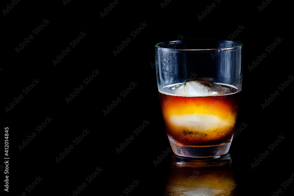 ice ball in glass of whisky on a reflective black table. ice ball in glass of whisky on a reflective black table.