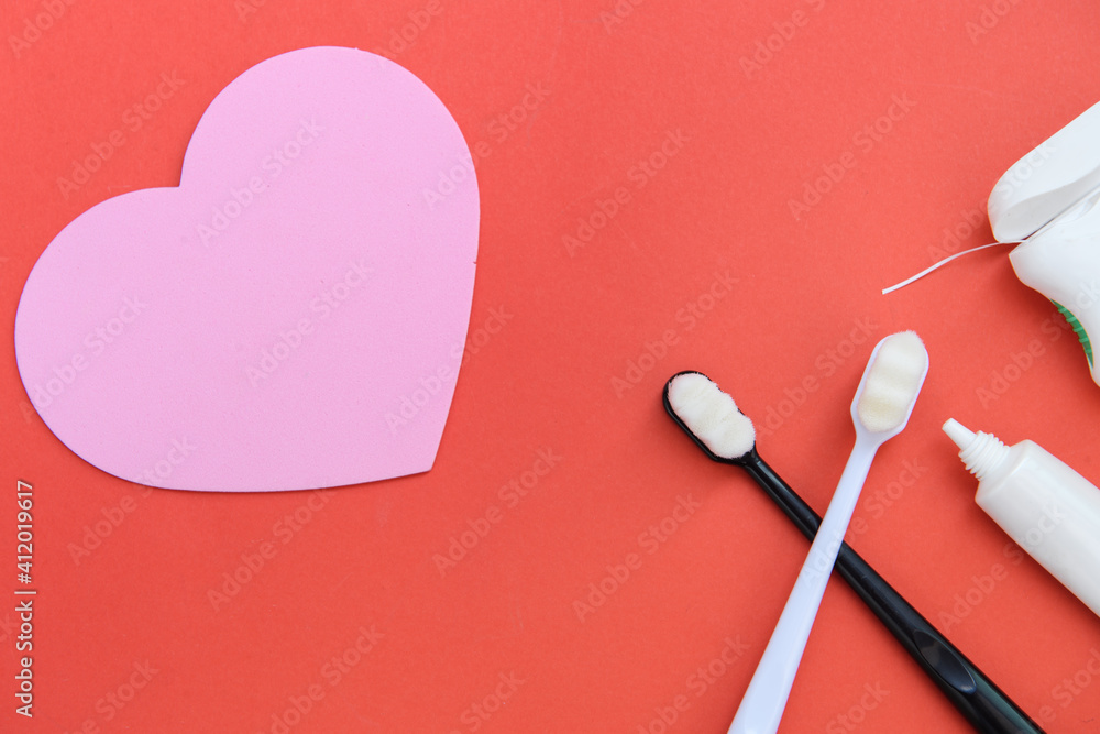 Two toothbrushes black and white handles and toothpaste and dental floss on red background. Valentines day concept. Two toothbrushes black and white handles and toothpaste and dental floss on red background. Valentines day concept.