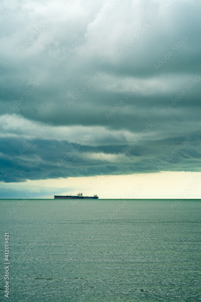 Seaview with ships in Port Dickson. Heavy clouds in rainy season. The image contain soft focus, noise and grain.