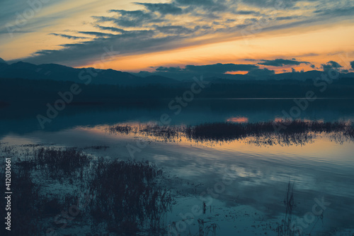 Beautiful sunset over lake in the winter.Mountains in background.