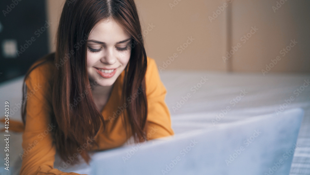 pretty woman lies in front of a laptop in the room work close-up pretty woman lies in front of a laptop in the room work close-up
