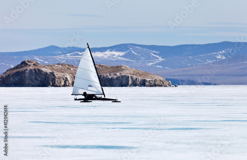 Baikal Lake. A tourist-athlete moves by the force of the wind under sail on a speed skating boat - boeier through the frozen Small Sea Strait. Active winter recreation