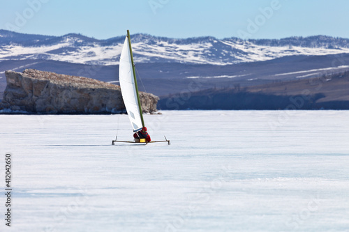 Baikal Lake. A tourist travels under a sail on a ice-skating ice boat - boeier across frozen Small Sea Strait. Active winter holidays