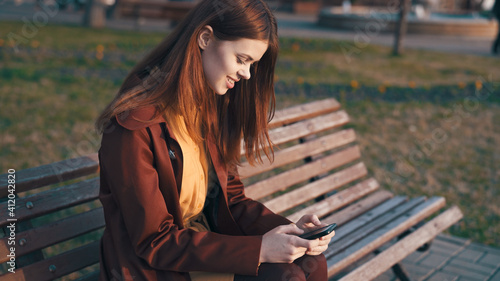 woman in the park sitting on a bench with a phone in her hands chatting outdoors