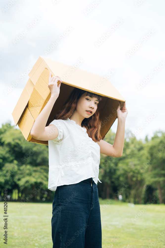 Obraz premium Hipster woman playing cardboard box putting it over head.