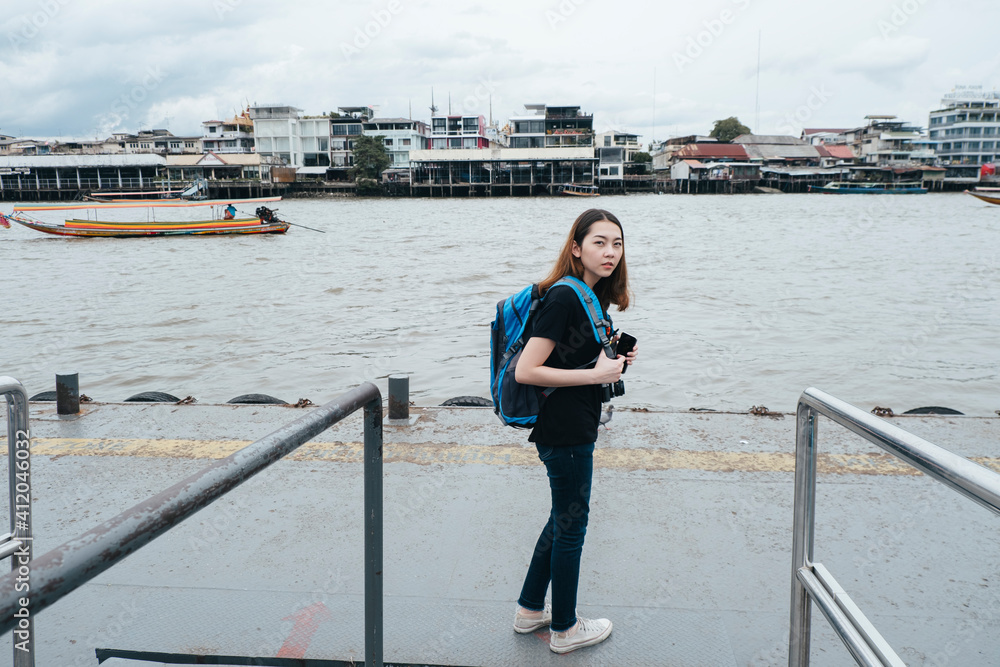 Backpacker woman waiting for a boat at Chao Praya river.