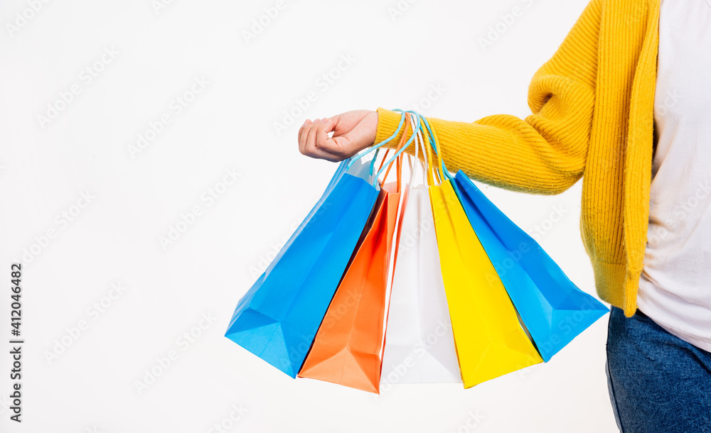 Happy woman hand she wears yellow shirt holding shopping bags multicolor, young female hold many packets within arms isolated on white background, Black Friday sale concept Happy woman hand she wears yellow shirt holding shopping bags multicolor, young female hold many packets within arms isolated on white background, Black Friday sale concept