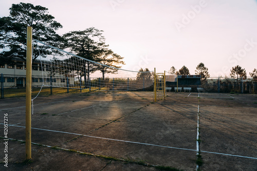Old beat-up cement volleyball courts with yellow poles and sunset behind.