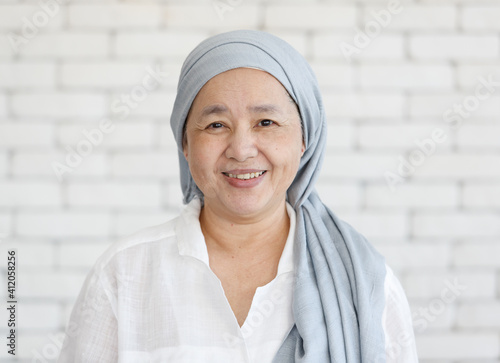 Portrait of an Asian woman with a clothe covered head and smile with happiness to the camera. Concept of a cancer patient with effected of chemo treatment but still feel hope and strength photo