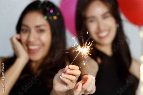 Two young and beautiful sexy Asian girls in a black dress playing with small little fireworks with fun and happiness in celebrating party