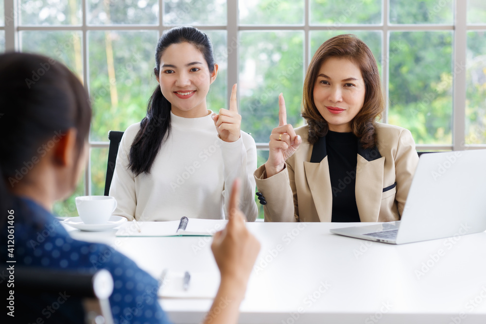 Fototapeta premium Deaf translator teaching two businesswomen to use and understand hand language sign. They are displaying number 1 symbal.