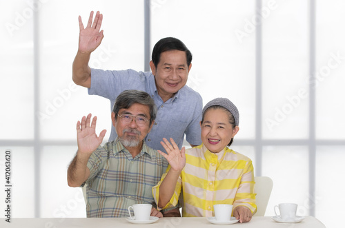 A Group of three senior Asian people, grandparents join together, show hands for greeting and smiling with happy to camera, Concept for happiness lifestyle of the older generation photo