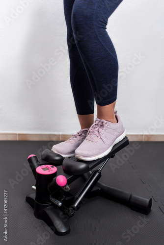 Vertical photography of woman's legs on a stepper machine. Fitness girl training cardiovascular to burn calories.