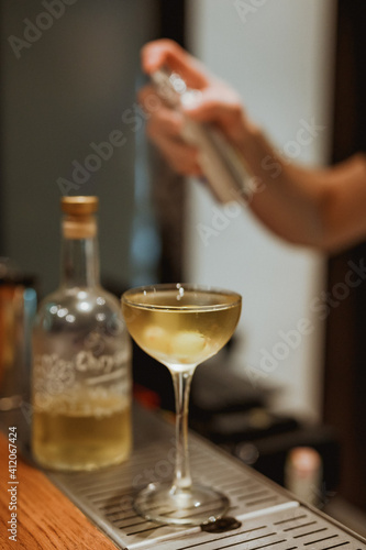 A sour cocktail in a coupe glass with garnish on bar counter. Lifestyle vertical image. Selective focus.