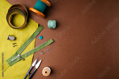 Fabric and sewing tools for needlework on a brown background, flat flat, top view, copy space. Creating fashion clothing concept. Horizontal background for advertising or packaging