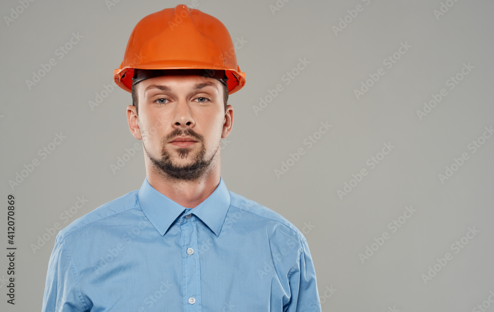 Male architect in orange paint and in a blue shirt on a gray background portrait Male architect in orange paint and in a blue shirt on a gray background portrait