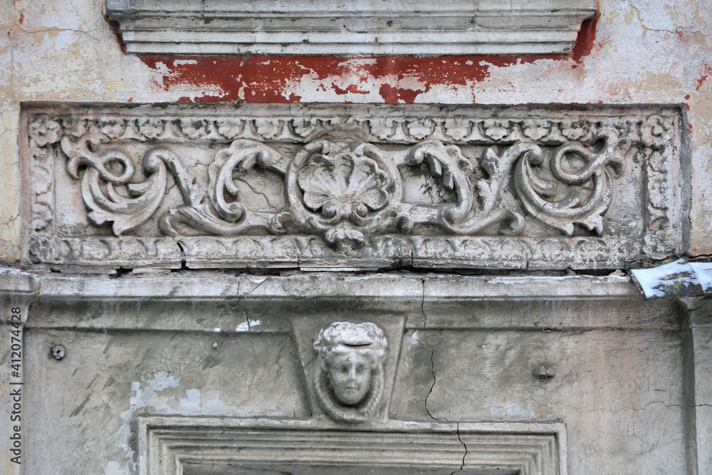 Elements of the architectural decor of the building. A fragment of the wall of an old stone house with peeling plaster.