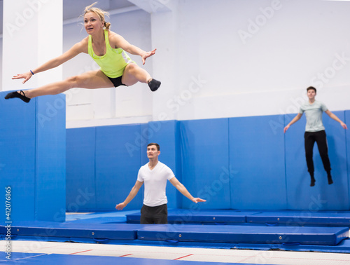 Athletic young woman training jumping movements in indoor trampolines center