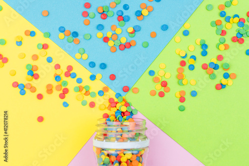 Pop colors. Festive multicolored background with bright sugar sprinkles scattered on paper.