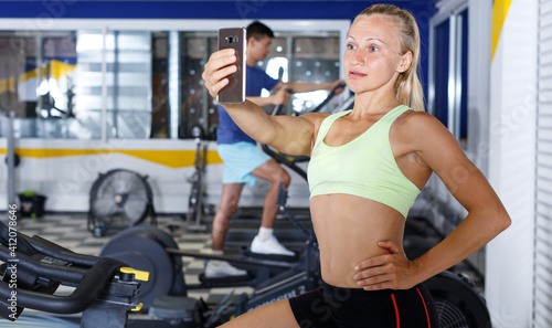 Female athlete taking selfie during training in fitness center