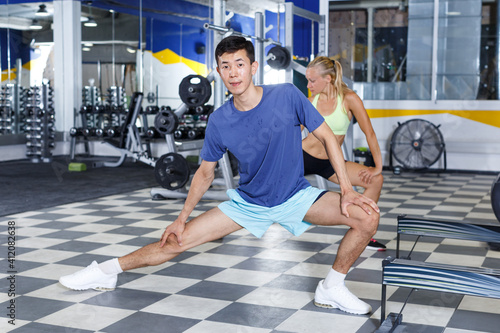 Positive fitness couple warming up during indoors stretching workout