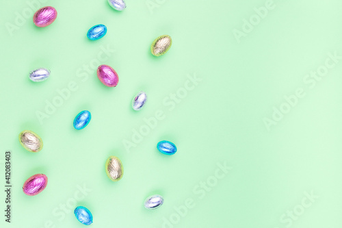 Green paper texture with chocolate candy eggs, Easter background, horizontal, copy space