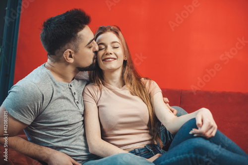 Caucasian couple lying on a couch and smile embracing while man is kissing his girlfriend