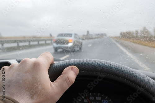 Canvas Print view of the driver's hand on the steering wheel of a car that is driving on the