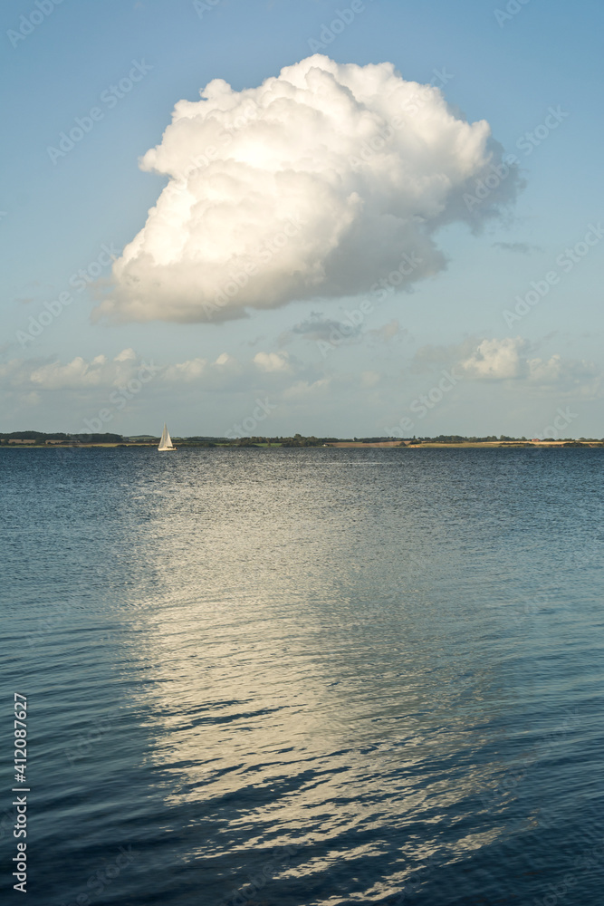 Vertical shot of beautiful white cumulus cloud over calm Baltic Sea in Northern Germany