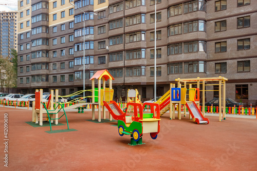 Colorful children playground in courtyard of new modern high-rise residential building. Urbanized environment without trees and lawns © Alexey Slyusarenko