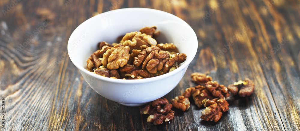 peeled walnuts in the white bowl close on brown old wooden table. healthy food concept. banner peeled walnuts in the white bowl close on brown old wooden table. healthy food concept. banner
