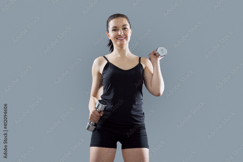 Athletic muscular young woman doing exercise using dumbbells Athletic muscular young woman doing exercise using dumbbells