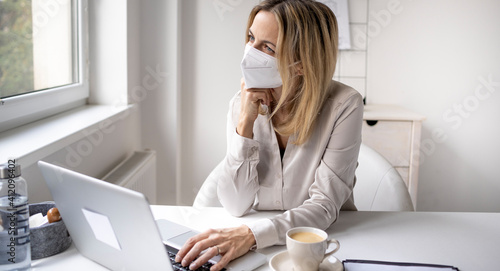 Corona office challenge, business woman wearing ffp2 mask working on laptop in office