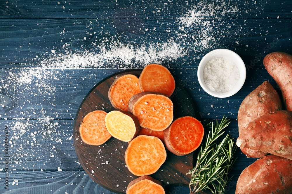 Composition of Fresh ripe sweet potatoes, spices, kitchenware on a wooden table background. Close-up. Composition of Fresh ripe sweet potatoes, spices, kitchenware on a wooden table background. Close-up.