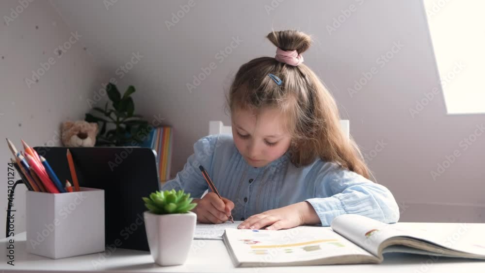 Home schooling, home school online. Caucasian cute little girl doing homework using a tablet and is very tired. Video footage 4k. Studying at home and during the quarantine period Home schooling, home school online. Caucasian cute little girl doing homework using a tablet and is very tired. Video footage 4k. Studying at home and during the quarantine period