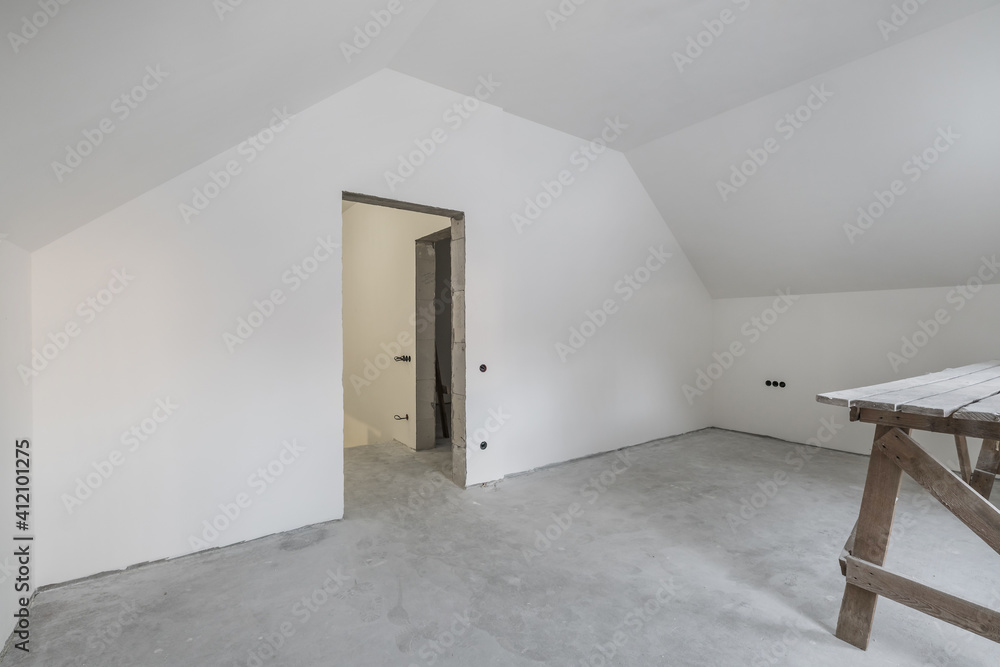 empty white room with mansard without repair and furniture with scaffolding empty white room with mansard without repair and furniture with scaffolding