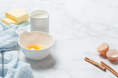 Cooking dessert concept. Fresh raw ingredients  eggs  cream and butter on white background  copy space. Background frame for baking. .