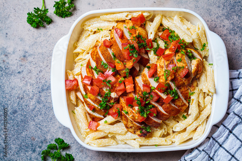 Foto Cajun chicken pasta with cheese and tomato in white dish.
