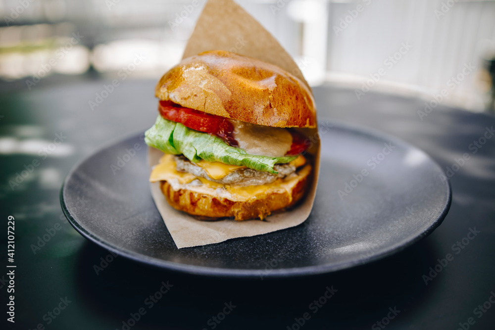 juicy burger in brown paper on a black plate